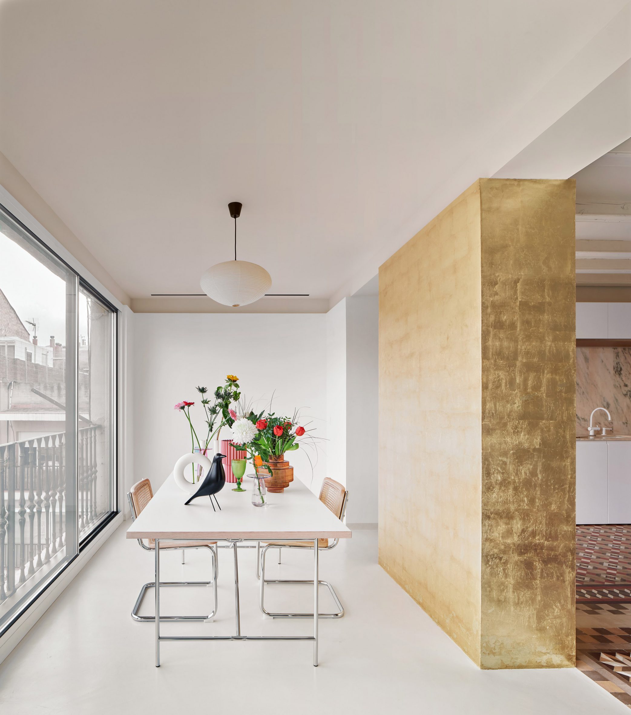 Dining space separated from kitchen by a gold-leaf wall