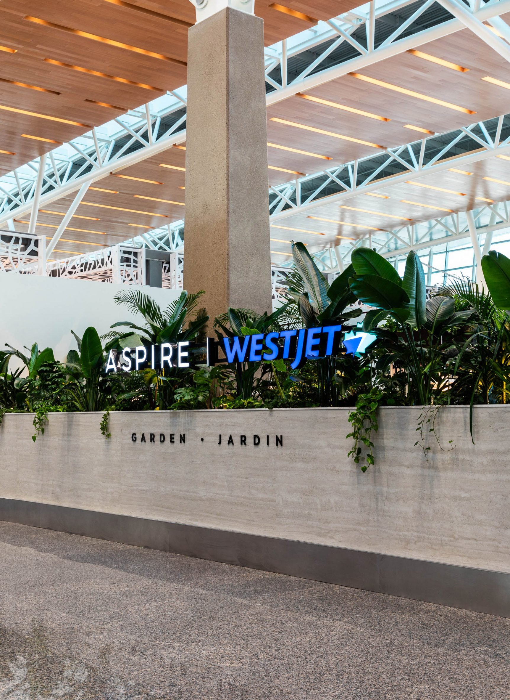 Glowing sign that reads "Aspire | WestJet" within lush planting