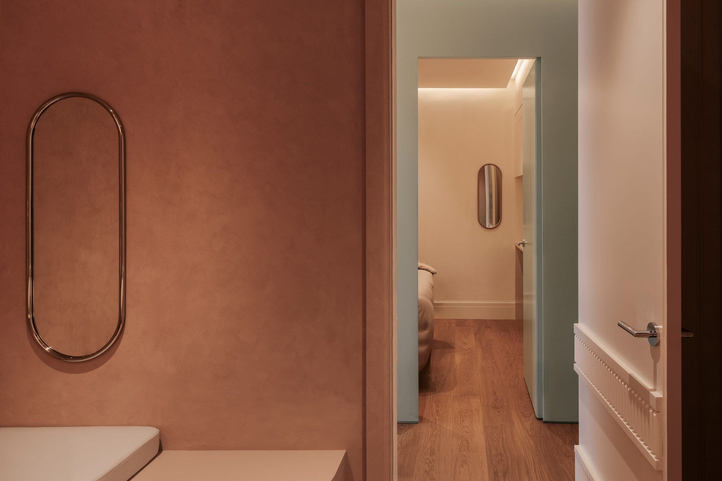 Treatment room with an earthy palette, looking out to a corridor accented in a glossy mint-toned finish
