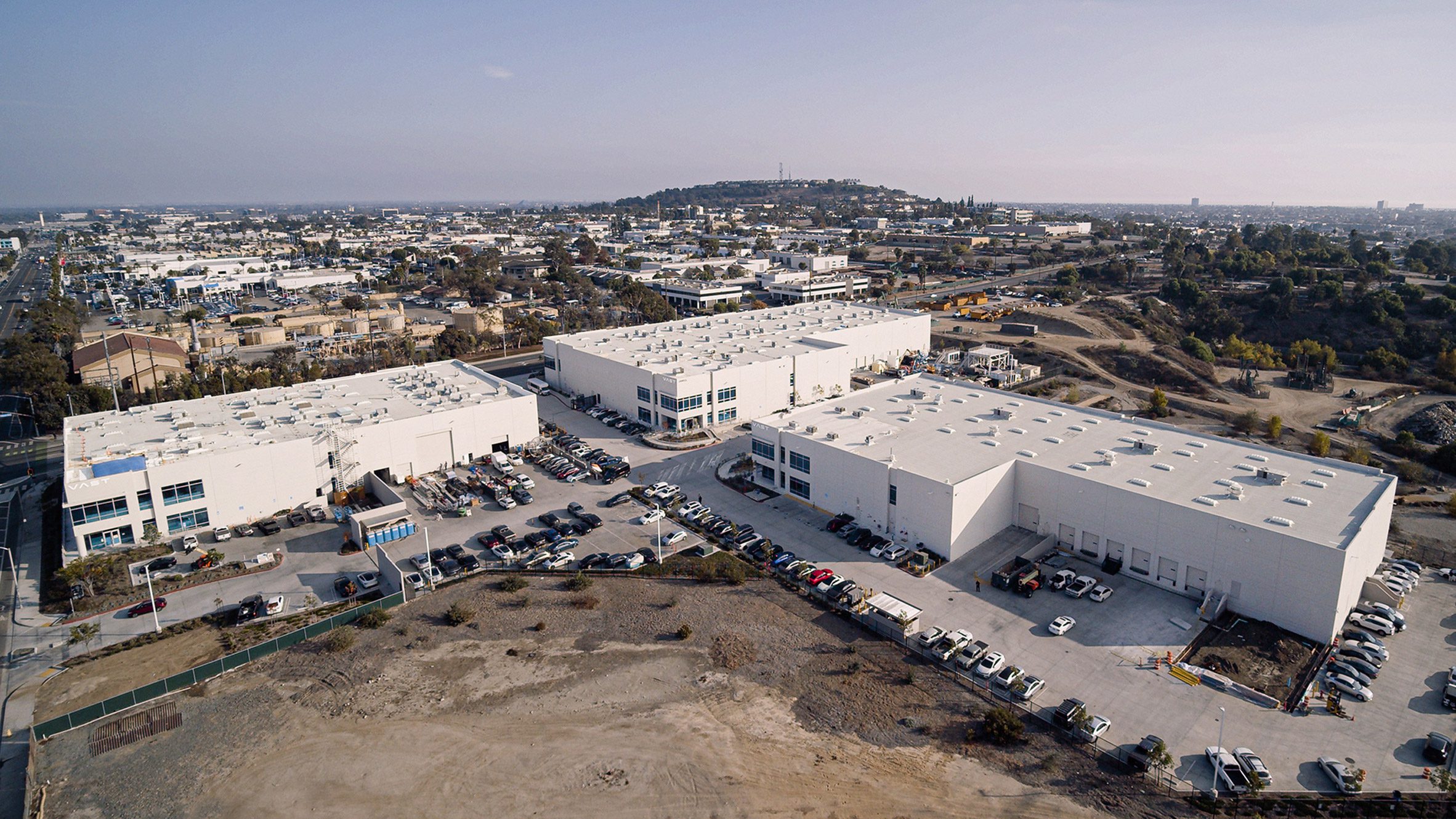 Aerial photo of Vast's Long Beach headquarters, showing three large white warehouses surrounded by car parking