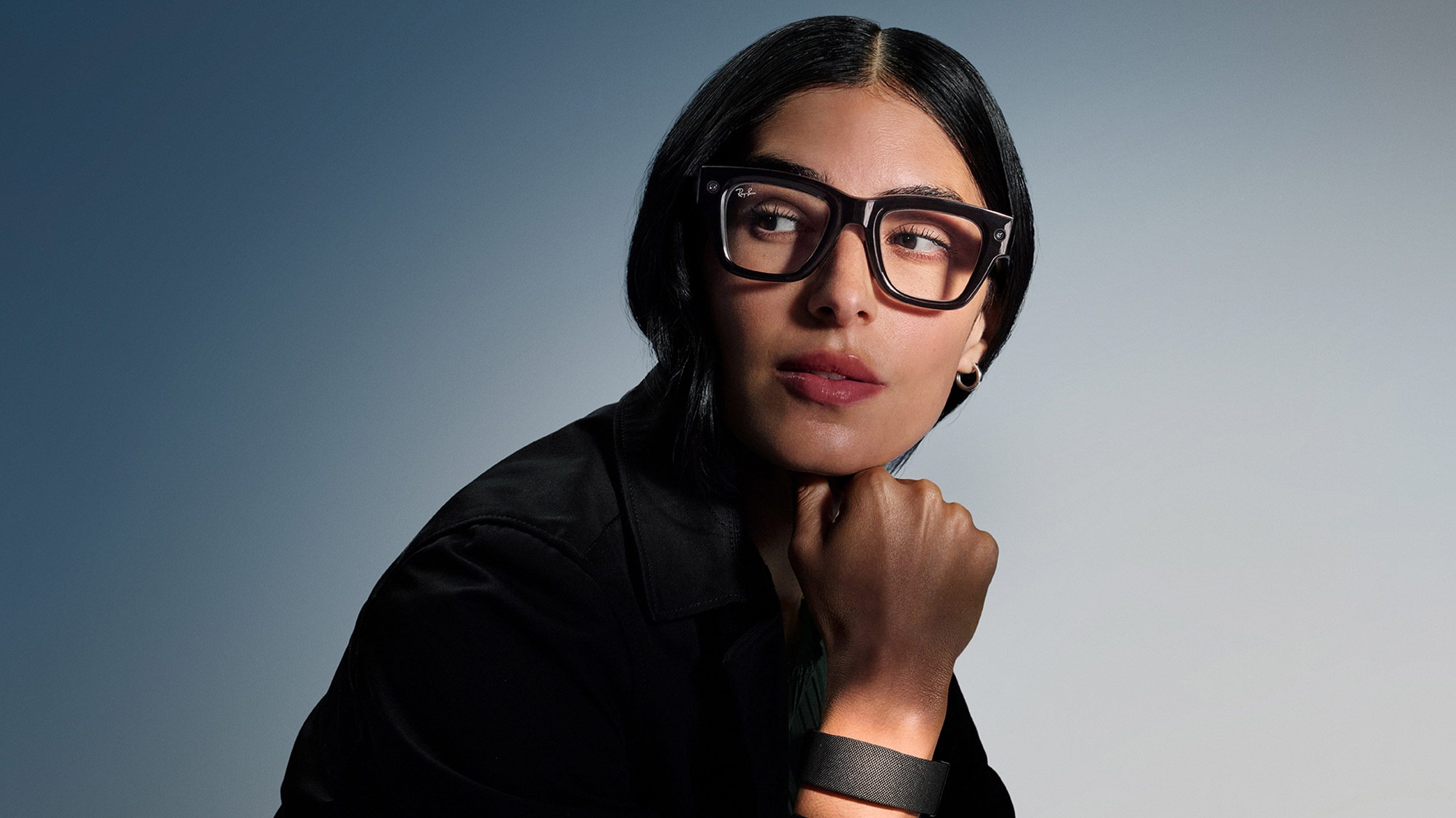 Photo of a woman wearing the Meta Ray-Ban Display glasses and Neural Band wristband
